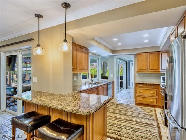 kitchen with sink, a breakfast bar area, stainless steel appliances, ornamental molding, and kitchen peninsula