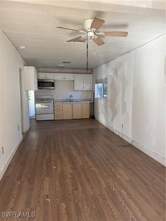 kitchen with sink, dark hardwood / wood-style floors, ceiling fan, white gas stove, and white cabinetry