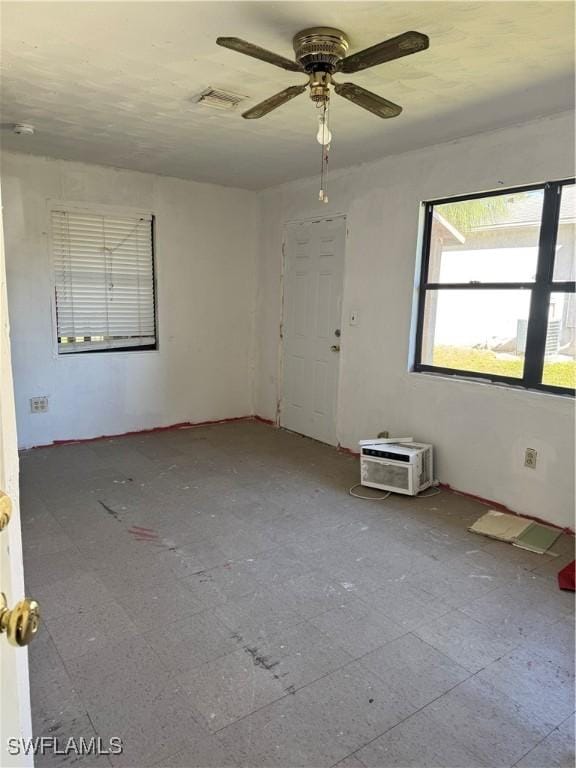 spare room with a wall unit AC and ceiling fan