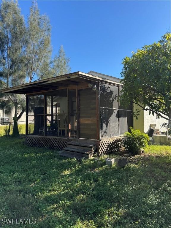 rear view of property with a lawn and a sunroom