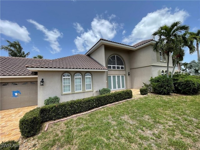 mediterranean / spanish-style home featuring a garage and a front yard