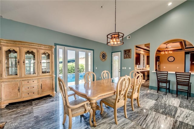 dining area with lofted ceiling, french doors, and an inviting chandelier