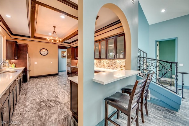 kitchen featuring tasteful backsplash, sink, a kitchen breakfast bar, a notable chandelier, and kitchen peninsula