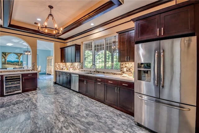 kitchen featuring sink, beverage cooler, backsplash, a tray ceiling, and stainless steel appliances