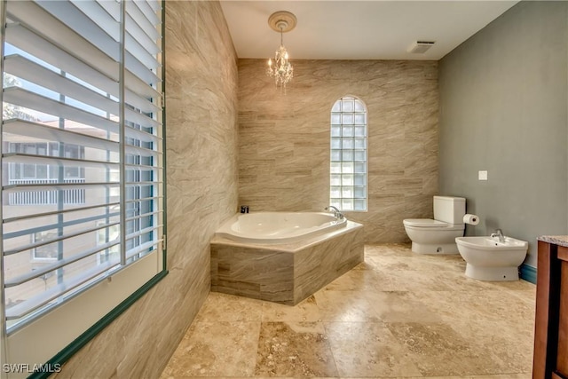 bathroom featuring toilet, a bidet, tiled tub, and a wealth of natural light