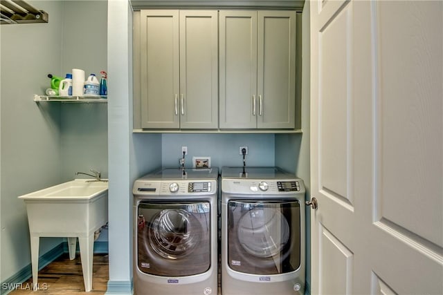 laundry area featuring cabinets, separate washer and dryer, hardwood / wood-style flooring, and sink