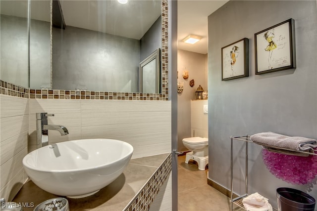 bathroom featuring tile walls, tile patterned flooring, toilet, and sink