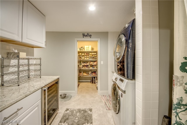 washroom with beverage cooler, bar area, cabinets, and stacked washer / drying machine