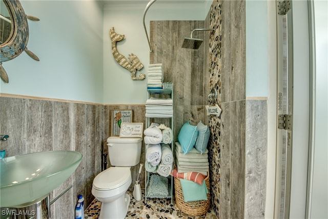 bathroom featuring toilet, walk in shower, tile patterned floors, crown molding, and tile walls