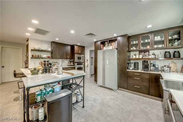 kitchen featuring appliances with stainless steel finishes, tasteful backsplash, dark brown cabinets, and a textured ceiling