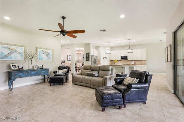 living room with light tile patterned flooring and ceiling fan with notable chandelier