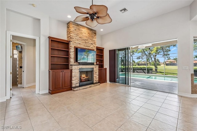 unfurnished living room featuring light tile patterned floors, baseboards, recessed lighting, ceiling fan, and a stone fireplace