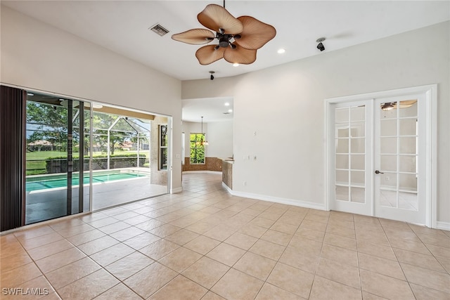 tiled spare room featuring ceiling fan and french doors