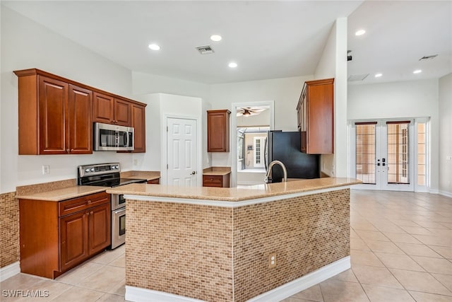 kitchen with kitchen peninsula, french doors, appliances with stainless steel finishes, and light tile patterned floors