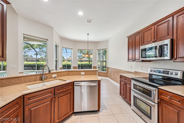 kitchen featuring light tile patterned flooring, sink, decorative light fixtures, dishwashing machine, and stove