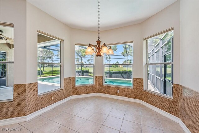 unfurnished dining area with plenty of natural light, light tile patterned flooring, and a chandelier