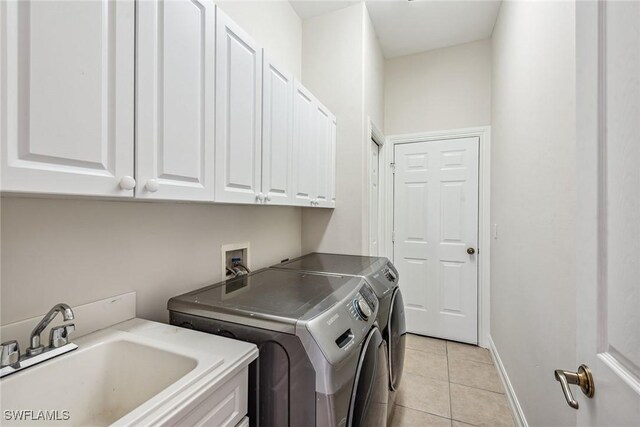 clothes washing area featuring independent washer and dryer, light tile patterned flooring, sink, and cabinets