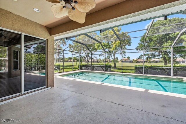 view of pool with ceiling fan, glass enclosure, and a patio area