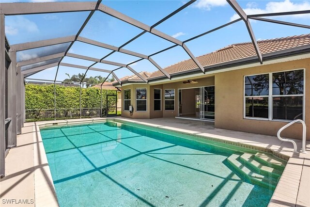 view of swimming pool featuring ceiling fan, glass enclosure, and a patio area