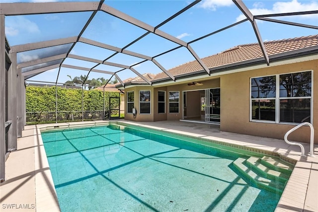 outdoor pool featuring glass enclosure, a patio, and ceiling fan