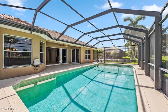 view of pool with glass enclosure, a patio, and ceiling fan