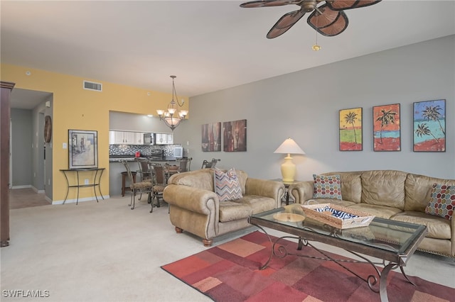 living room with ceiling fan with notable chandelier and light colored carpet