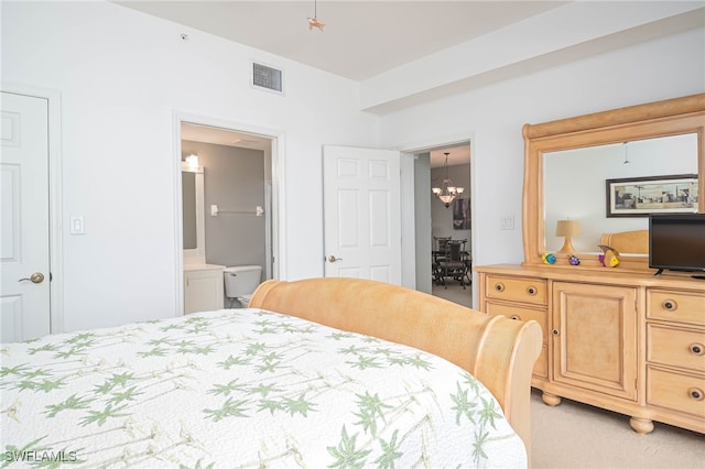 carpeted bedroom with ensuite bath and a chandelier