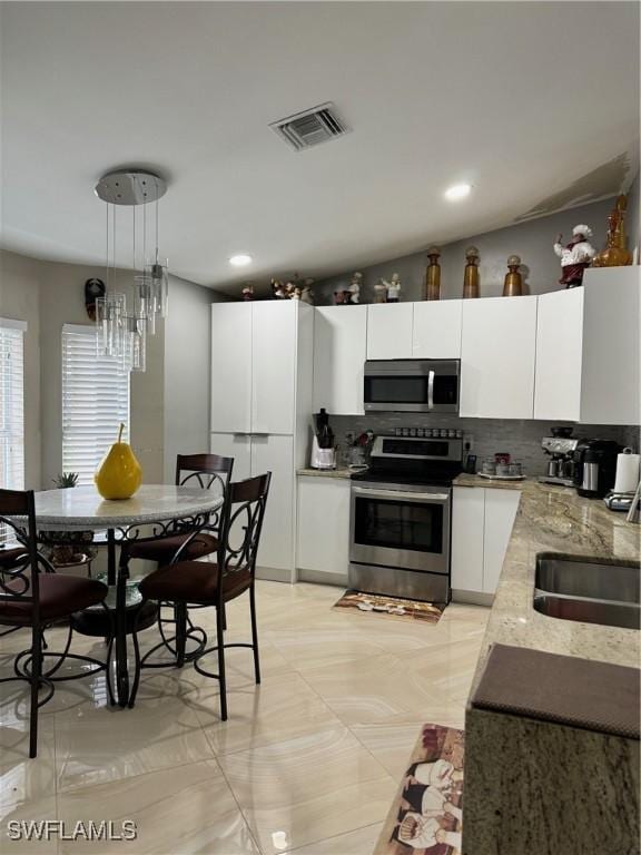 kitchen with sink, white cabinetry, tasteful backsplash, decorative light fixtures, and stainless steel appliances