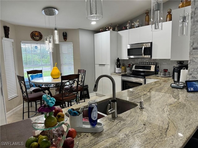 kitchen with white cabinetry, tasteful backsplash, light stone counters, hanging light fixtures, and stainless steel appliances