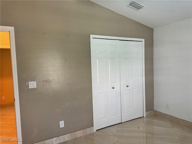 unfurnished bedroom featuring lofted ceiling and a closet