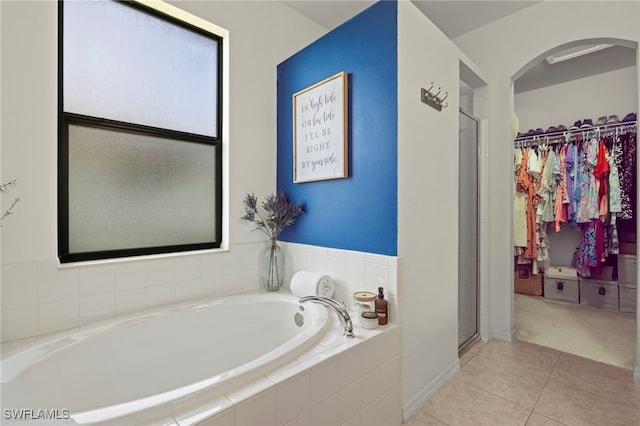 full bathroom featuring a stall shower, tile patterned flooring, a garden tub, and a walk in closet