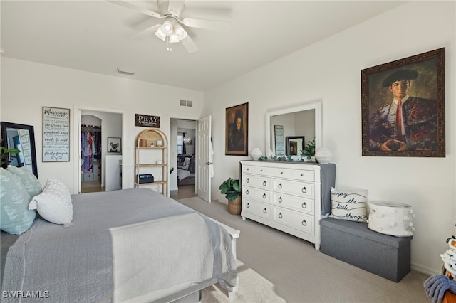 bedroom featuring a walk in closet, carpet flooring, visible vents, and a ceiling fan