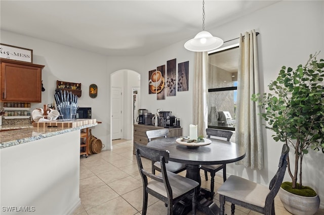 dining room with light tile patterned floors and arched walkways