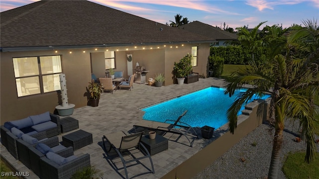 pool at dusk with outdoor lounge area and a patio area