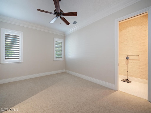 carpeted spare room featuring ornamental molding, a healthy amount of sunlight, and ceiling fan