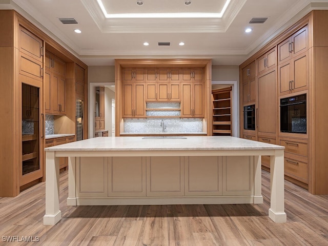 2835 Silverleaf Ln, Naples, FL 34105 - kitchen with black oven, light countertops, light wood finished floors, tasteful backsplash, and a raised ceiling