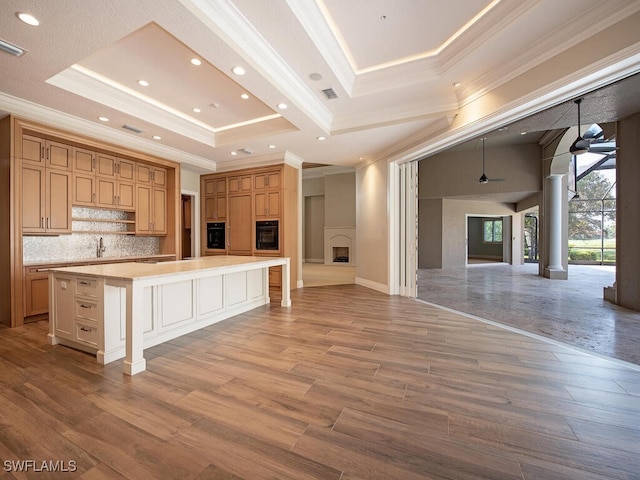 2835 Silverleaf Ln, Naples, FL 34105 - kitchen with black oven, ornamental molding, a raised ceiling, tasteful backsplash, and light countertops