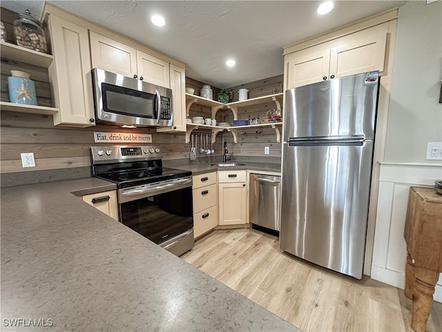 kitchen with light hardwood / wood-style flooring, appliances with stainless steel finishes, cream cabinetry, and sink