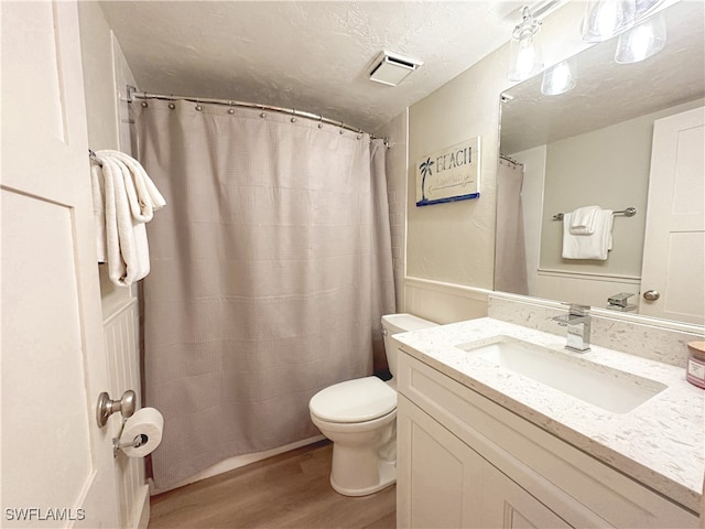 bathroom featuring a textured ceiling, toilet, vanity, and wood-type flooring