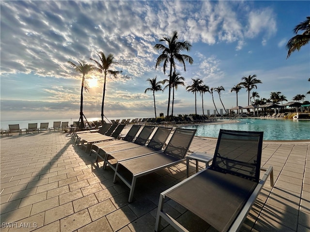 patio terrace at dusk featuring a community pool