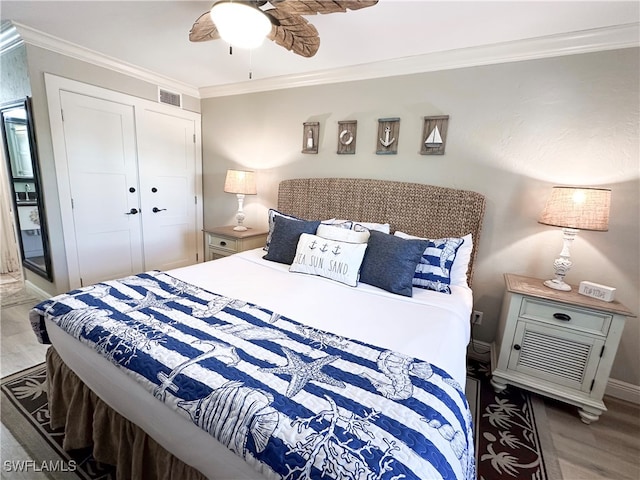 bedroom featuring ceiling fan, ornamental molding, hardwood / wood-style flooring, and a closet