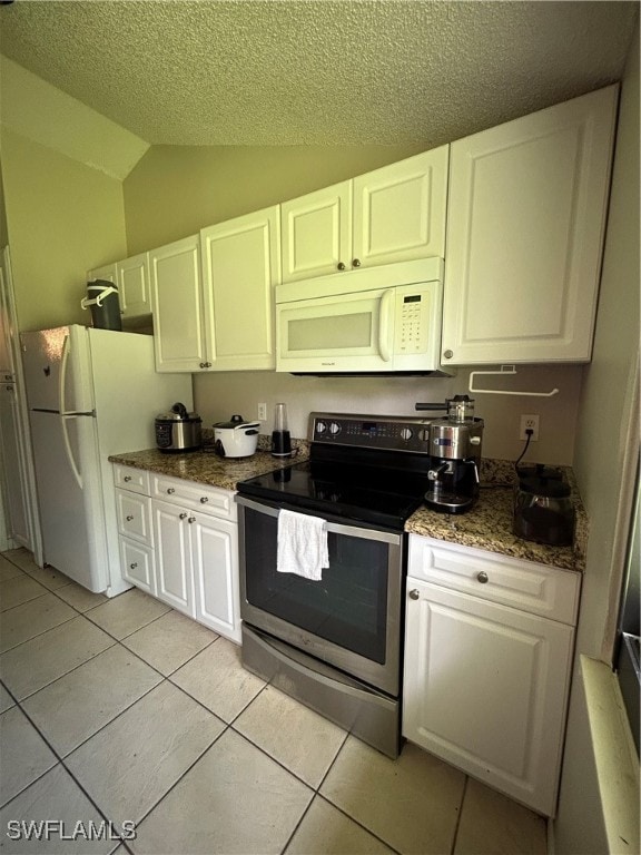 kitchen with a textured ceiling, white appliances, light tile patterned floors, vaulted ceiling, and white cabinetry