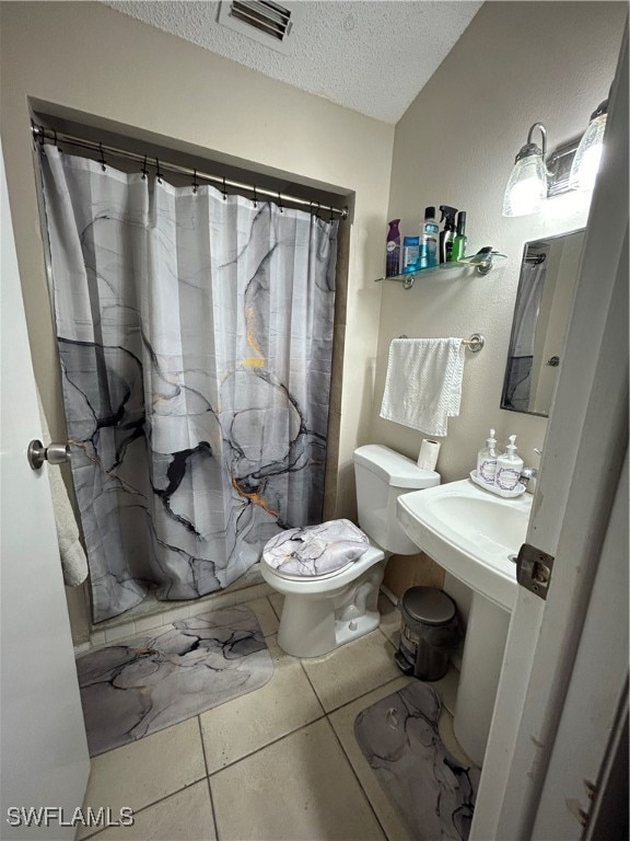 bathroom with tile patterned floors, a textured ceiling, and toilet