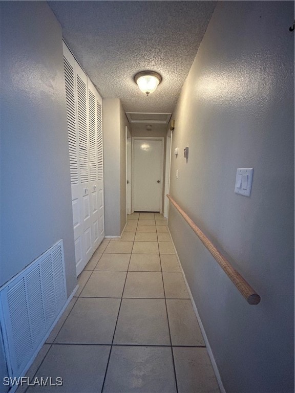 hallway featuring a textured ceiling and light tile patterned floors