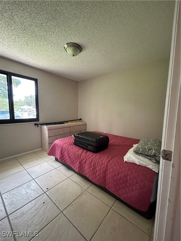 bedroom with a textured ceiling and light tile patterned floors