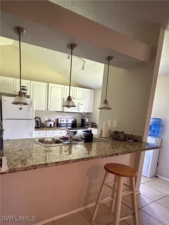 kitchen featuring a textured ceiling, white appliances, hanging light fixtures, vaulted ceiling, and light tile patterned flooring