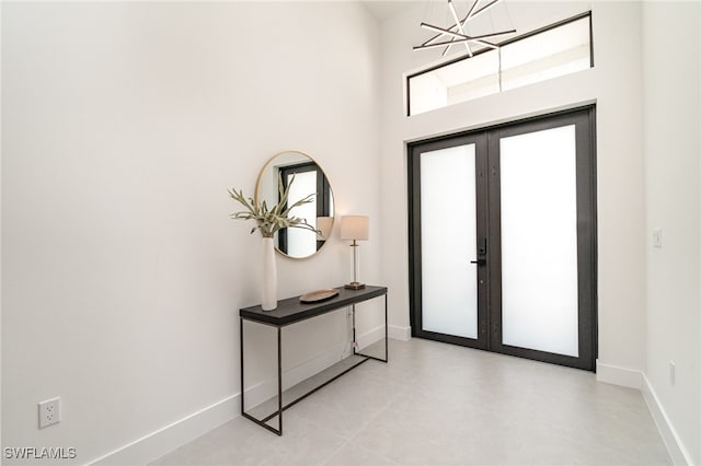 foyer entrance featuring a high ceiling, an inviting chandelier, and french doors