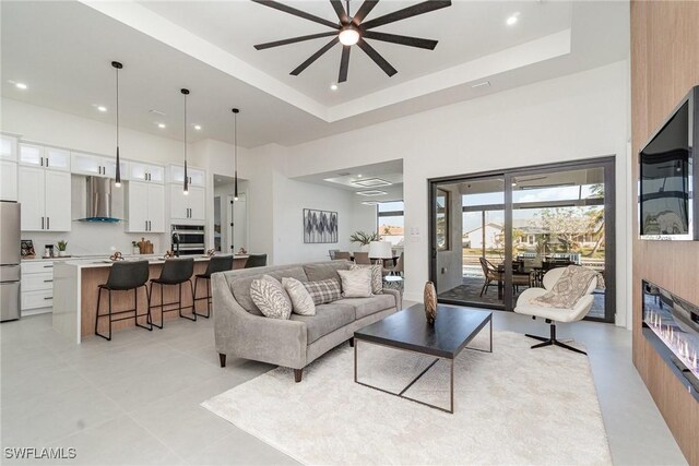 tiled living room with a tray ceiling and ceiling fan