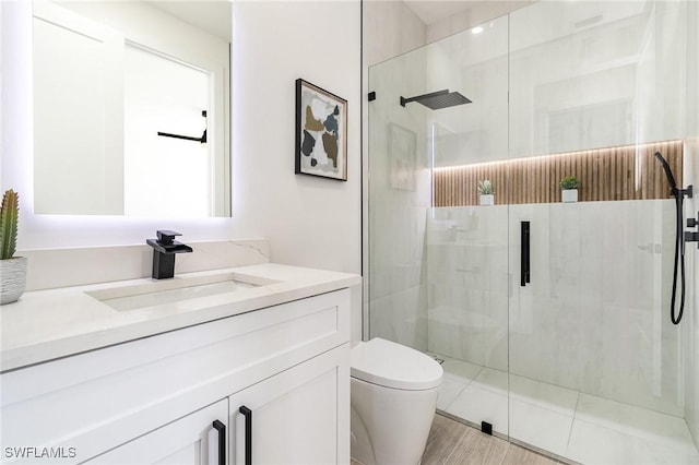 bathroom with vanity, a shower with shower door, and toilet