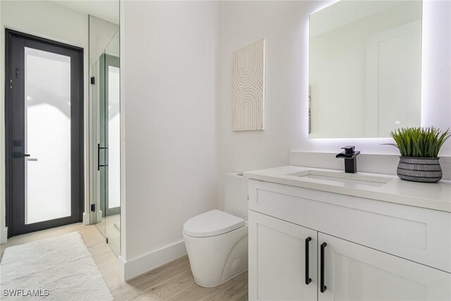 bathroom with hardwood / wood-style flooring, vanity, and toilet